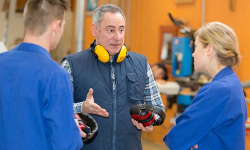 Image of teacher in trade school with students to contrast a lack of similar opportunities in CI industry which is partially responsible for talent shortage.
