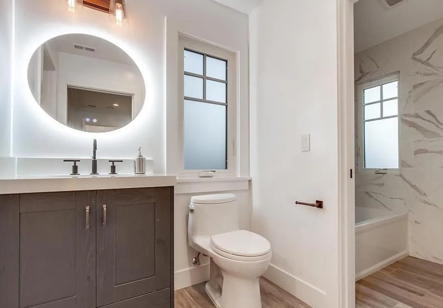 Smart bathroom backlit LED mirror with modern colorations and hardwood flooring marble tiles