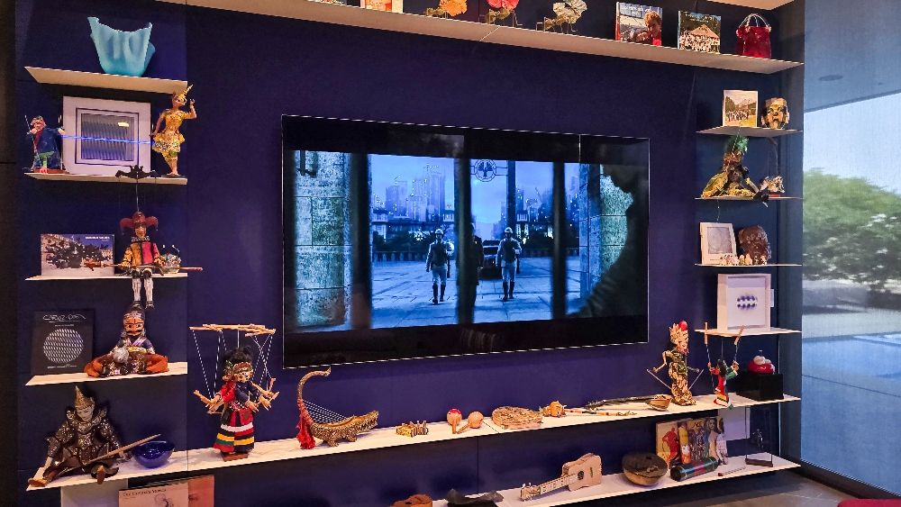 Wall mounted TV over small sculptural art pieces on floating shelves