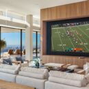 Large open media room with large luxurious display overlooking Los Angeles skyline set in rich natural wood accent wall