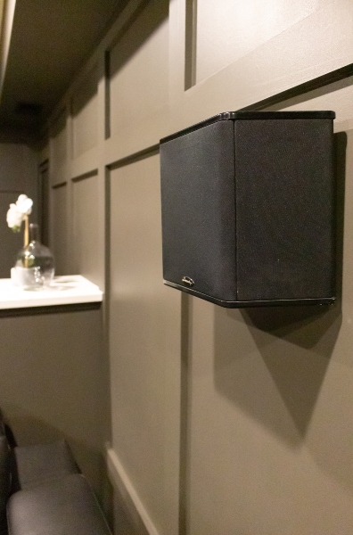 Hanging subwoofer on accent wall with decorative moldings in custom home theater by Gramophone Bowie, Maryland.